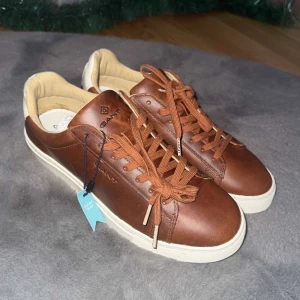 Bruna sneakers från Gant - Snygga bruna sneakers från Gant i skinn med vita sulor och färgglada detaljer på undersidan. Skorna har snörning och en stilren design som passar perfekt för vardagsbruk.