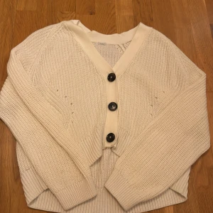 Vit stickad kofta från Lindex - Mysig vit stickad kofta från Lindex med stora knappar framtill. Lappen har försvunnit men jag skulle säga att den passar 152-164 i barnstorlek. Jag säljer den eftersom den inte kommer till användning längre! 💕