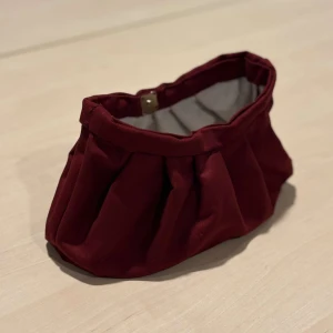 Vinröd clutchväska - Snygg vinröd clutchväska med guld knapp. Perfekt för att bära med sig det viktigaste. Enkel och stilren design som passar till många tillfällen.❤️