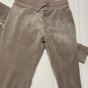  mjukisbyxor med strassdetaljer - Snygga beige mjukisbyxor i mjukt material med ordet 'Love' i strass på benet. Perfekta för en avslappnad stil med en touch av glamour.