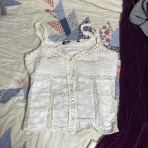 Vit spetsdetaljerad topp från Zara - Säljer en söt vit topp från Zara med spetsdetaljer och volangkant. Toppen har smala axelband och ett vackert blommönster. Perfekt för en somrig look! Pris kan diskuteras!❤️🥰🩷
