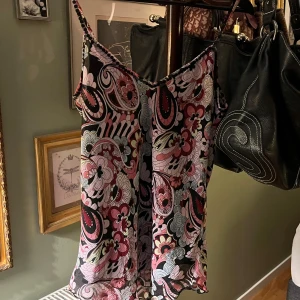 Mönstrad linne i rosa och svart - Snygg linne med ett färgglatt mönster i rosa, svart och vitt. Den har smala axelband och en luftig passform, perfekt för varma dagar.