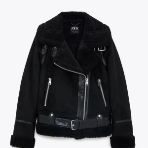 Svart jacka från Zara - Snygg svart jacka från Zara med dragkedja och bälte. Jackan har en cool design med flera dragkedjor och en fluffig krage. Perfekt för att hålla stilen i kallare väder. Säljer då den inte kommer till användning längre. Pris kan diskuteras