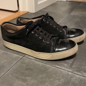 Lanvin cap toe  - Snygga svarta sneakers med snörning och vit sula. Köptes i London för 5000kr. Följs med Lanvin kartong och påse. Vid snabb affär kan jag tänka mig lite lägre pris. Storlek 45 passar även 44 väldigt bra. Bara höra av sig om fler bilder. 