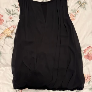 Svart klänning från Stockh LM - Elegant svart klänning från Stockh LM i storlek S. Klänningen har en stilren design med en lätt v-ringad hals och ärmlös stil, perfekt för en chic look.