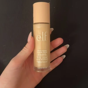 e.l.f. Halo Glow Liquid Filter - Säljer en e.l.f. Halo Glow Liquid Filter i en ljus nyans. Denna flytande produkt ger en strålande finish och kan användas som en bas eller highlighter för att skapa en glödande look.