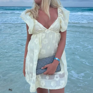 Ljusgul blommig klänning - Säljer en superfin ljusgul klänning med blommigt mönster. Den har volangdetaljer vid axlarna och en söt, luftig passform som är perfekt för sommardagar vid stranden. Använd en gång 💛