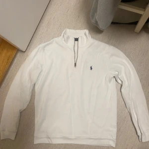 Vit Zip Polo tröja - Säljer en stilren vit tröja från Polo Ralph Lauren i storlek M. Säljs för att den inte passar mig längre och den är i bra skick. Säljs för grymt pris.