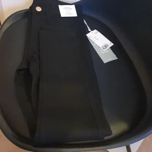 Svarta skinny jeans från H&M - Säljer ett par svarta skinny jeans från H&M i nytt skick. Deh är gjorda av återvunnet material. Perfekta för både vardag och festliga tillfällen. Passar barn i åldern 8-9 år.