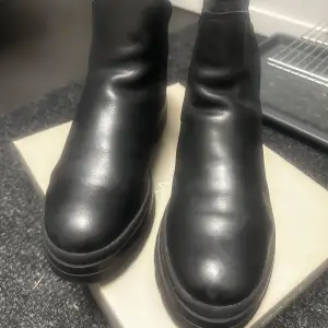 Säljer ett par snygga svarta boots från GANT i skinn. De har en stilren design med elastiska paneler på sidorna för enkel på- och avtagning. Perfekta för höst och vinter med en robust sula som ger bra grepp. Skorna är i nytt skick och kommer i originalkartong. Nypris 1900kr.