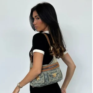 Vintage Louis Vuitton-väska - Snygg axelväska i jeansmaterial med monogrammönster. Väskan har bruna läderdetaljer och flera praktiska fickor med dragkedja och spännen. Perfekt för vardagsbruk och ger en cool, avslappnad stil.