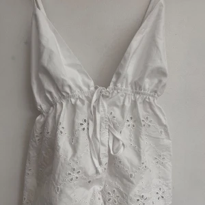Vitt broderat zara linne - Säljer ett superfin vit linne med broderade blommor. Den har justerbara axelband och en söt knytning framtill. Aldrig använd och köpt på zara, säljs inte längre!