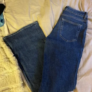 Blå bootcut jeans - Säljer ett par snygga blå bootcut jeans i bra skick. De har en klassisk femficksdesign med dragkedja och knapp framtill. Perfekta för både vardag och fest! Passar bra till vinterns kalla dagar.
