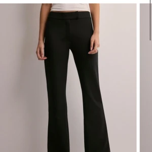Svarta kostymbyxor - Populära KEEP IT UP flare pants från nelly!Snygga svarta kostymbyxor i högmidjad modell. De har en elegant bootcut-stil som ger en klassisk look. Perfekta för både kontoret och festliga tillfällen. Passar bra med en enkel topp eller en mer formell blus. Slutsålda på Nelly. Säljer då jag valde fel storlek. Använd en gång.