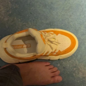 Orange och vita sneakers - Säljer ett par coola sneakers i orange och vitt. De har en chunky sula och snörning framtill. Perfekta för att sticka ut i mängden och superbekväma att ha på sig hela dagen. Passar perfekt till både vardag och fest!