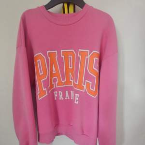 Säljer en superfin rosa sweatshirt från Gina Tricot i storlek XS. Den har ett coolt tryck med texten 'Paris France' i vitt och orange på framsidan. Perfekt för en avslappnad stil eller en dag på stan. Tröjan är i bra skick och redo för en ny ägare! Det är en liten fläck där fram men inget man tänker på!🩷