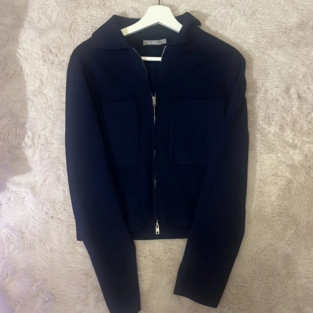 Säljer en stilren mörkblå jacka med dragkedja framtill. Jackan har långa ärmar och två stora fickor i fram. Perfekt för höst och vår, och ger en snygg look till vardagsoutfiten. Passar bra till både jeans och kjol! . Neuletakit & Villapaidat.