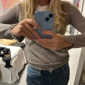 Glittrig brun tröja - Säljer en snygg glittrig brun tröja med v-ringning. Tröjan har långa ärmar och en bekväm passform.