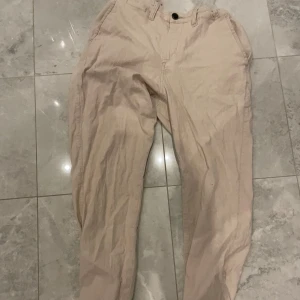 Beige linnebyxor - Säljer ett par snygga beige linnebyxor i bra skick. De har en normal passform och är perfekta för både vardag och fest. Byxorna har knappar och dragkedja framtill. Passar bra till både t-shirt och skjorta för en stilren look. Stockholm closet💫