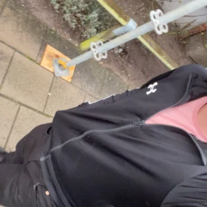 Svart bomberjacka med dragkedja - Säljer en snygg svart underarmor jacka med dragkedja framtill. Jackan har en stilren design med en liten logga på bröstet. Perfekt för höst och vår, och funkar både till vardags och fest. Passar bra till jeans eller chinos för en avslappnad look. 500 kr nypris