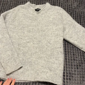 Grå stickad tröja  - Mysig grå stickad tröja från selected  i bra skick. Perfekt för kyliga dagar med sin mjuka och varma känsla. Tröjan har en klassisk design med rund hals och långa ärmar. Passar perfekt till både jeans och kjol för en avslappnad look.
