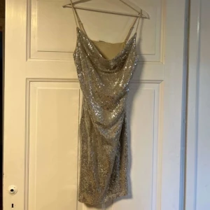 Glittrig klänning från Vero Moda - Säljer en superfin glittrig klänning från Vero Moda i storlek S. Den är täckt med silverpaljetter. Perfekt för festliga tillfällen! Klänningen är i nytt skick med etikett kvar.