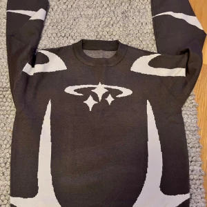 Svart och vit tröja med mönster - Säljer en cool svart tröja med vitt grafiskt mönster. Den har långa ärmar och en rund halsringning. Perfekt för höst och vinter, och den är i bra skick. 