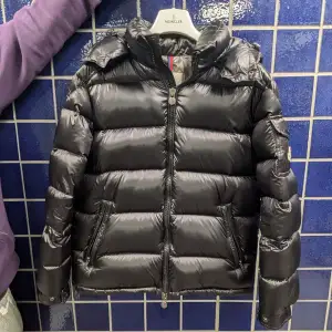 Säljer en snygg svart dunjacka från Moncler i mycket bra skick. Jackan har en quiltad design med dragkedja och en praktisk ficka på ärmen. Perfekt för kalla vinterdagar och håller dig varm och stilren. Passar både till vardags och festliga tillfällen. Kvitto tillkommer såklart.