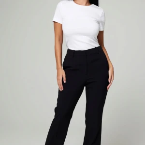 Kostymbyxor  - Säljer en klassisk vit t-shirt i bomull. Den har en normal passform och korta ärmar, perfekt för vardagsbruk eller att styla upp med accessoarer. Enkelt och stilrent plagg som passar till allt!