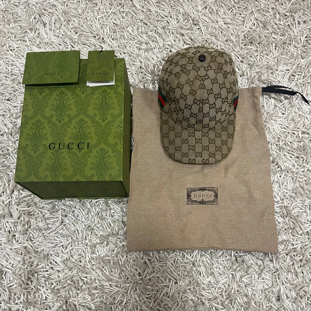 Säljer en snygg beige Gucci keps. Kepsen har en justerbar rem baktill och detaljer i rött och grönt på sidorna. Perfekt för att ge din outfit en lyxig touch. Kommer med originalförpackning och dustbag.. Accessoarer.