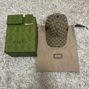 Gucci keps  - Säljer en snygg beige Gucci keps. Kepsen har en justerbar rem baktill och detaljer i rött och grönt på sidorna. Perfekt för att ge din outfit en lyxig touch. Kommer med originalförpackning och dustbag.