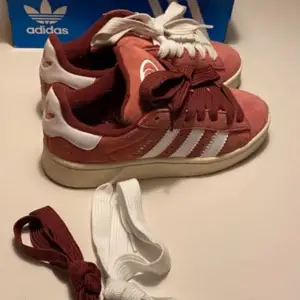 Säljer ett par snygga rosa Adidas Campus! Endast använda vid 2 tillfällen i somras så passa på att göra ett bra köp till ett kanonbra pris för ett par nya skor! De har de klassiska tre vita ränderna på sidan och kommer med både vita och vinröda skosnören. Skorna är i mycket bra skick och perfekta för både vardag och fest. Storlek är dam 36 men skulle säga 37 passar bra då jag har den storleken och de passar mig perfekt!. Kommer med originalkartong. 🌸