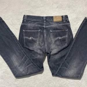 Grå jeans från Nudie Jeans - Snygga grå jeans från Nudie Jeans med en klassisk femficksdesign. De har en straight passform och är tillverkade i slitstarkt denim. Perfekta för en avslappnad stil med en touch av edge.