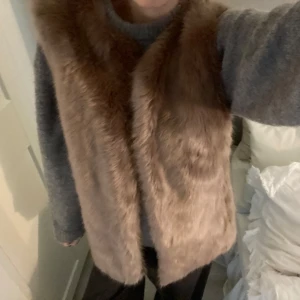 Brun pälsväst från Oasis - Säljer en snygg brun pälsväst från Oasis. Västen är perfekt för att hålla sig varm och stilren under kyligare dagar. Den har en mjuk och fluffig textur som ger en lyxig känsla.