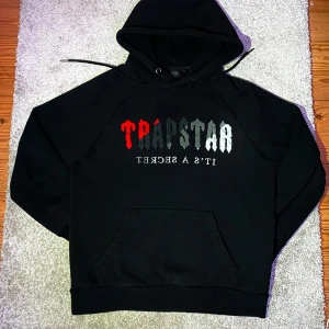 Trapstar Tracksuit - Trapstar Tracksuit – Storlek M – Använd men i fint skick – 499 SEK  Säljer min Trapstar tracksuit i storlek M. Den är använd men fortfarande i bra skick, utan några skador eller hål – bara vanliga tecken på användning. Perfekt för dig som vill ha en stilren och bekväm tracksuit till ett bra pris!  Färg: Svart med röd/grå/vit text Model: Trapstar Tracksuit  Nypris: 2228 SEK  Pris: 499 SEK.       Hör av dig om du har frågor!