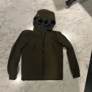 Olivgrön cp company jacka - Säljer en olivgrön Shell-R cp&co jacka. Hög dragkedja med goggles. Sparsamt använd inga skador eller märken på linserna. Vind och element kapabel jacka med justerbart midjespänne. Säljer på grund av att jag vuxit ur den. Pris kan diskuteras vid snabb affär 