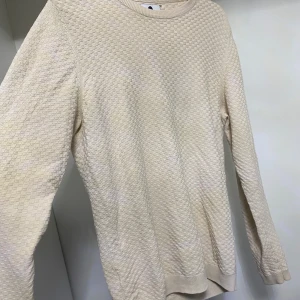 Beige stickad tröja - Säljer en stilren beige stickad tröja med ett diskret mönster. Tröjan har långa ärmar och rund halsringning, perfekt för kyligare dagar. Passar bra till jeans. Ett litet hål, men inget man tänker på och som märks om man har t-shirt under. Hör av dig vid intresse!