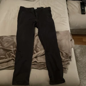Svarta byxor - Snygga svarta byxor med normal passform. De har en klassisk design med knappar och dragkedja framtill. Perfekta för en stilren look.