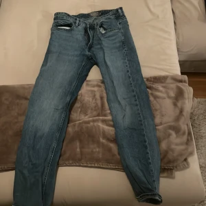 Blå jeansbyxor - Säljer ett par klassiska blå jeansbyxor med normal passform. De har en traditionell femficksdesign och en knappgylf. Perfekta för en avslappnad stil.