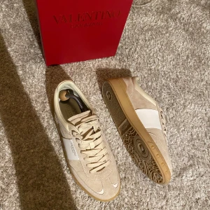 Beige sneakers från Valentino Garavani - Snygga beige sneakers från Valentino Garavani av modellen Upvillage med vit detalj på sidan. Skorna har en klassisk snörning och en bekväm gummisula. Perfekta för en stilren look. Nypris : 8200 kr Mitt pris: 4299. Pris ej hugget✅Skriv för mer info✅
