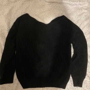 Svart stickad tröja - Säljer en svart stickad tröja med v-ringad design. Tröjan har långa ärmar och en ribbad struktur som ger en stilren look. Perfekt för kyligare dagar.