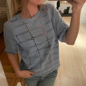 Ljusblå stickad tröja - Säljer en ljusblå stickad tröja med ett snyggt mönster. Tröjan har korta ärmar och en avslappnad passform, perfekt för vår och sommar. Den är både stilren och bekväm, ett måste i garderoben! 💙
