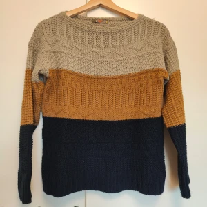 Flerfärgad stickad tröja - Säljer en mysig stickad tröja i tre färger: beige, senapsgul och mörkblå. Tröjan har ett snyggt mönster och långa ärmar. Perfekt för kyliga dagar!