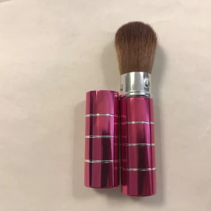 Mjuk Infällbar sminkborste i metallhylsa - Snygg och praktisk sminkborste med rosa metallhylsa och silverdetaljer. Perfekt för att ta med i väskan tack vare det kompakta formatet. Borsten är mjuk och idealisk för applicering av puder eller rouge. Helt ny, finns fler kvar 