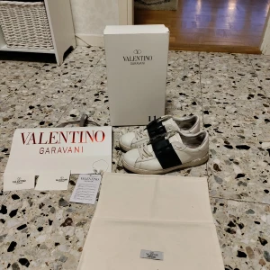 Valentino Garavani sneakers - Säljer ett par stilrena Valentino Garavani sneakers i vitt med svarta detaljer. Skorna har en klassisk design med snörning och är tillverkade i skinn. Perfekta för en trendig look. Skick 8.5/10 väldigt bra skick förutom sulan är lite smutsig men går att tvätta bort det nästa, och insidan har tappat lite färg. Allt og medföljer! Självklart riktiga✅ Pris är inte hugget i sten, kontakta mig om du har några funderingar, byten kan vara intressant 