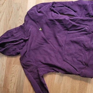 Lila/vinröd/plommonfärgad? hoodie från Lyle & Scott - Säljer en snygg hoodie från Lyle & Scott med deras ikoniska logga på bröstet. Tröjan har en klassisk känguruficka och en bekväm huva.. Perfekt för en avslappnad stil. Storlek L men passar som M