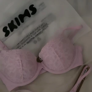 Behå Skims  - Säljer en superfin ljusrosa BH från Skims med spetsdetaljer. ”Fits Everybody Lace Push-Up Bra”. Den har justerbara axelband och en mjuk, bekväm passform med push-up. I nyskick, använd 1 gång. Strl: 32/34B (XS). Ord pris: 820 kr Pris kan diskuteras vid snabb affär. 
