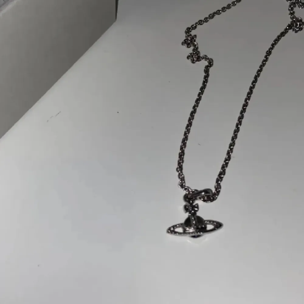 Säljer ett stilrent silverhalsband från Vivienne Westwood. Halsbandet har en ikonisk orb-berlock som ger en unik touch. Perfekt för att lyfta vilken outfit som helst, oavsett om det är till vardags eller fest.. Accessoarer.