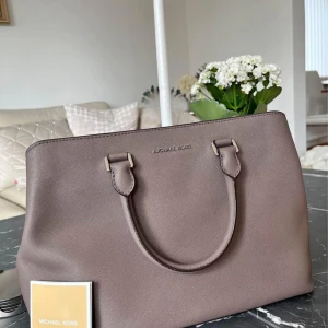 Beige/grå handväska från Michael Kors - Grå/beige handväska från Michael Kors i mycket bra skick. Knappt använd.  Köpt på Zalando, kvitto finns Saffiano läder Modell: Savannah Mått: 36*24*15