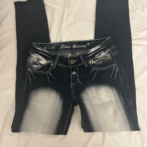 Blue Queen Jeans - Säljer ett par low waist mörkblåa jeans från Blue Queen med coola broderade detaljer på bakfickorna. De har en snygg fade framtill och en dragkedja vid fickan. De är skinny men jag har klippt en slit så de ser bootcut-ish från sidan